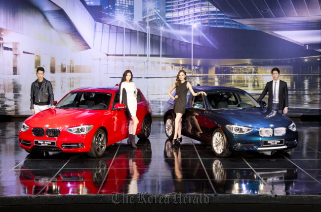Models pose with BMW’s new 1 Series hatchback at a launching event held in Seoul on Thursday.   BMW Korea