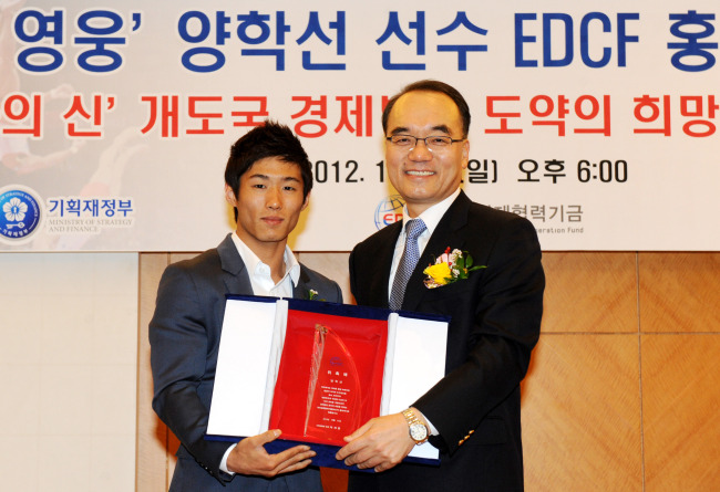 Strategy and Finance Minister Bahk Jae-wan (right) poses with Olympic gold medalist Yang Hak-seon after appointing him as a goodwill ambassador for the Economic Development Cooperation Fund, at Lotte Hotel, downtown Seoul, Sunday.   Yonhap News