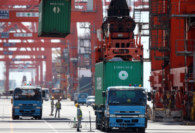 Workers look at an Evergreen Marine Corp. container being loaded at a shipping terminal in Tokyo.   Bloomberg
