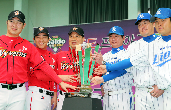 Samsung manager Ryu Joong-il (third from right), SK manager Lee Man-soo (third from left) and player representatives pose with the Korean Series trophy on Tuesday.   Yonhap News
