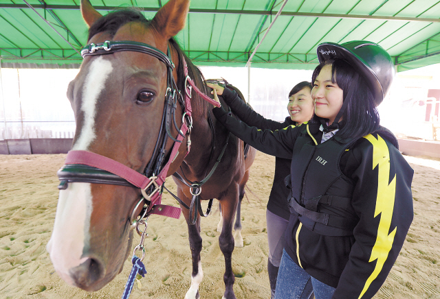 Young girls pet a horse at Riding Healing Center in Incheon. (Ahn Hoon/The Korea Herald)