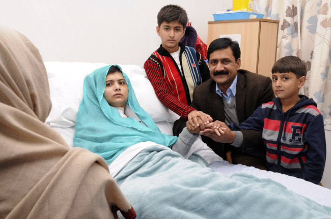 Malala Yousufzai in her hospital bed, poses for a photograph, with her father Ziauddin, second right accompanied by her two younger brothers Atal, right and Khushal, center. (AP-Yonhap News)