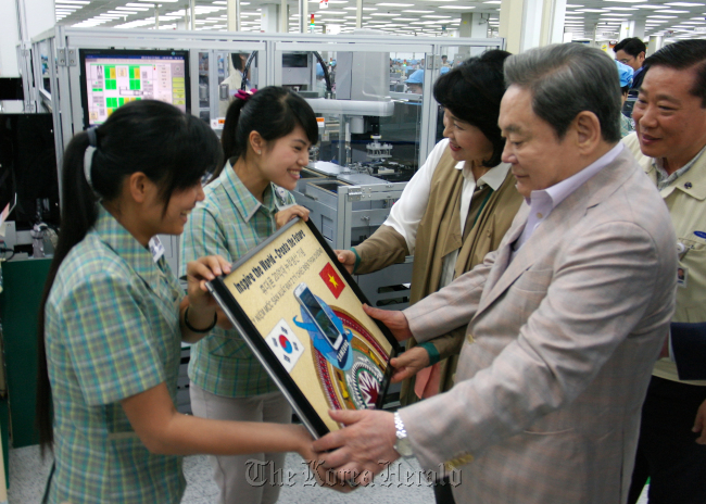 Samsung Electronics chairman Lee Kun-hee and his wife Hong Ra-hee receive a commemorative plaque from workers during their visit to a Vietnamese factory on Oct. 13.   Samsung Electronics