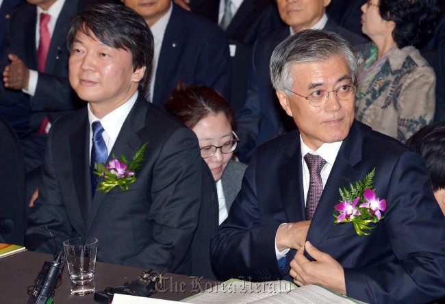 Independent presidential candidate Ahn Cheol-soo (left) takes his seat next to the Democratic United Party’s presidential candidate Moon Jae-in at a meeting for small retailers in Seoul on Tuesday.   Park Hyun-koo/The Korea Herald