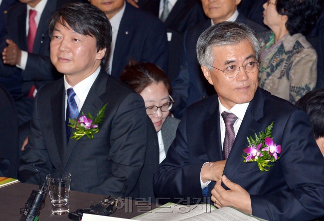 Independent presidential candidate Ahn Cheol-soo (left) takes his seat next to the Democratic United Party’s presidential candidate Moon Jae-in at a meeting for small retailers in Seoul on Tuesday.   Park Hyun-koo/The Korea Herald