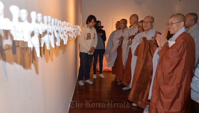 Officials of the Buddhist Jogye Order view artist Moon Jong-sun’s “Miss” at the “Self-Made Inspiration and Laughter Exhibition” at Sejong Museum of Arts in Seoul on Wednesday.   Lee Sang-sub/The Korea Herald