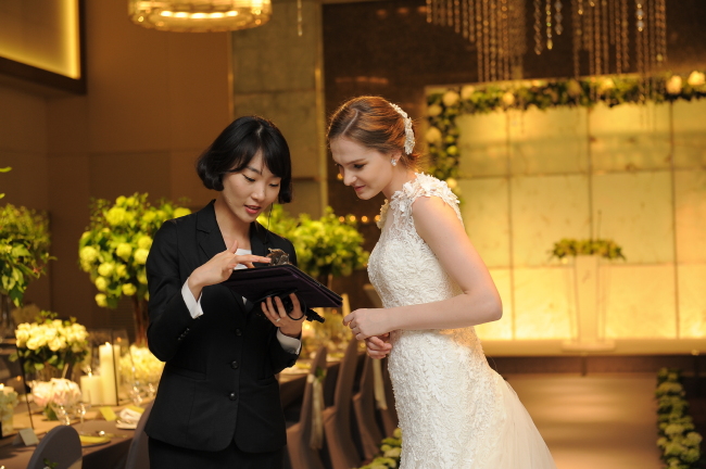 A wedding concierge talks with a bride on her planned ceremony at Hotel Plaza in Seoul.   Hotel Plaza