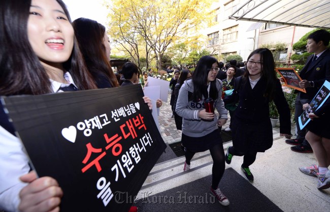 Friends and families of students taking a national college entry exam stand with placards that read “Best of luck,” during an orientation session in Seoul on Wednesday.   Park Hae-mook / The Korea Herald