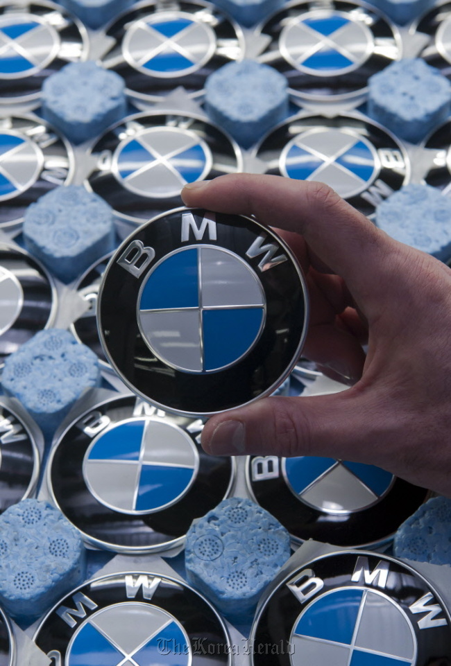 An employee holds a BMW badge at the company‘s assembly plant in Regensburg, Germany.   Bloomberg
