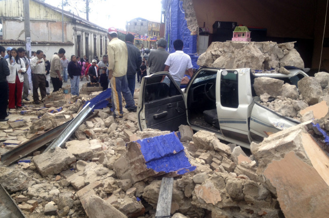 Photo provided by the radio La Red Deportiva shows residents standing near debris after an earthquake in San marcos, Guatemala, Wednesday. Xinhua-Yonhap News