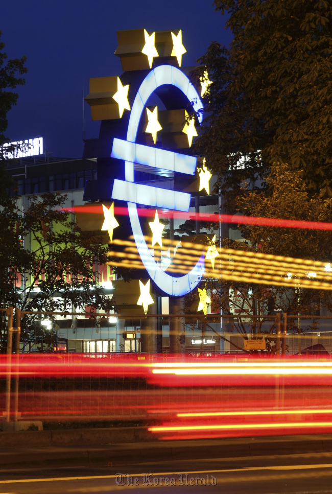 Light trails from passing automobiles are seen in front of the euro sign sculpture outside the headquarters of the European Central Bank in Frankfurt.   Bloomberg