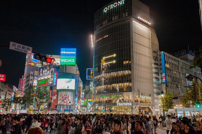 People cross an intersection at night in the Shibuya district of Tokyo.   Bloomberg