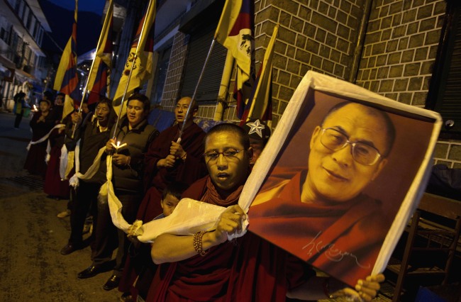 An exile Tibetan carries a portrait of the Tibetan spiritual leader the Dalai Lama during a candlelit vigil Dharmsala, India, Sunday.   AP-Yonhap News
