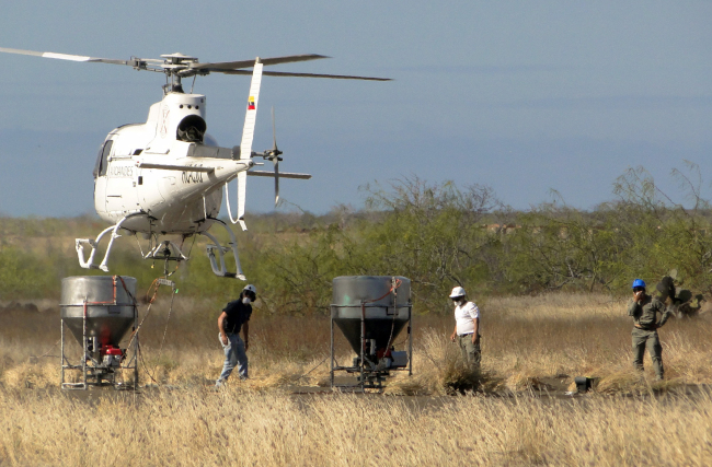 Galapagos National Park staff test equipment that will hold poisonous bait to kill rats on the Galapagos Islands, as they stand on Baltra Island.  AP-Yonhap News