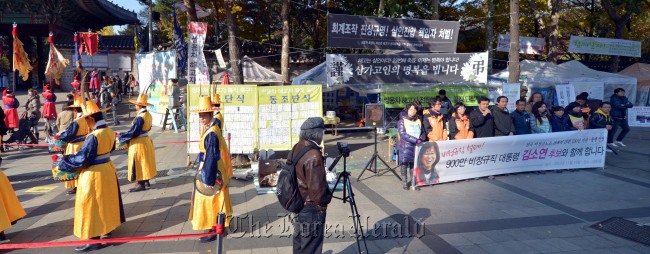 Labor unionists protest in front of Deoksu Palace in central Seoul on Thursday while a traditional court ritual is reenacted.   Kim Myung-sub/The Korea Herald