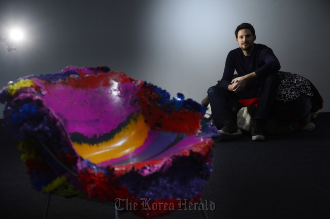 British artist Tom Price sits on the “Fleece Chair” made out of fleece. In the foreground is “PE Stripe Meltdown Chair.”   Park Hae-mook/The Korea Herald