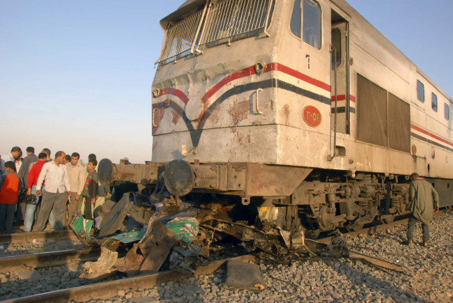 Egyptians gather at the site of a train crash that killed at least 51 people near Assiut in southern Egypt on Saturday.   AP-Yonhap News