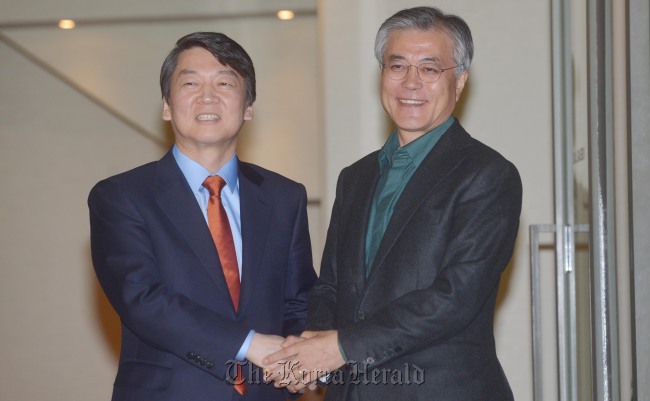 Democratic United Party presidential candidate Moon Jae-in (right) and independent candidate Ahn Cheol-soo clasp hands after they agreed to resume talks on a unified candidacy at a restaurant in Seoul on Sunday.   Kim Myung-sub/The Korea Herald