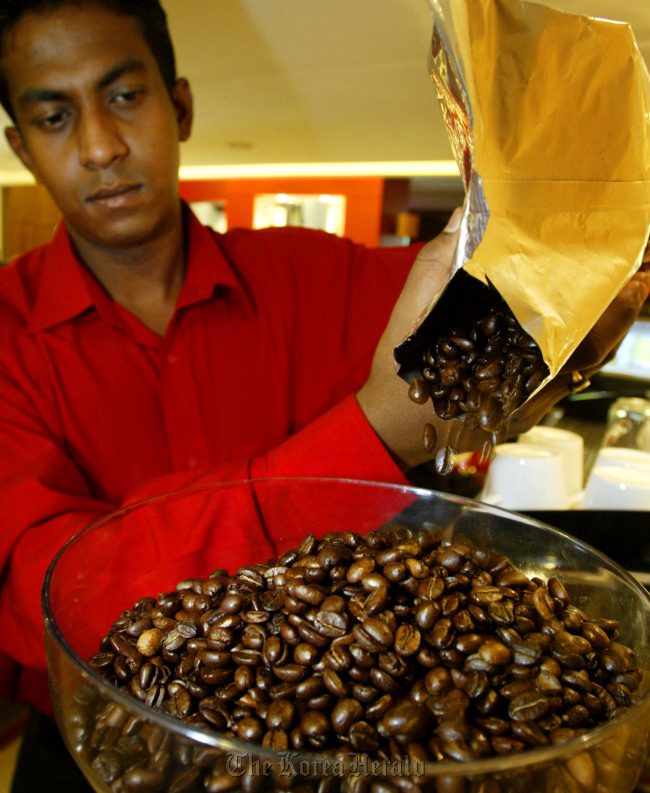 A cafe employee pours coffee beans into a grinder at a Cafe Coffee Day outlet in New Delhi, India.   Bloomberg