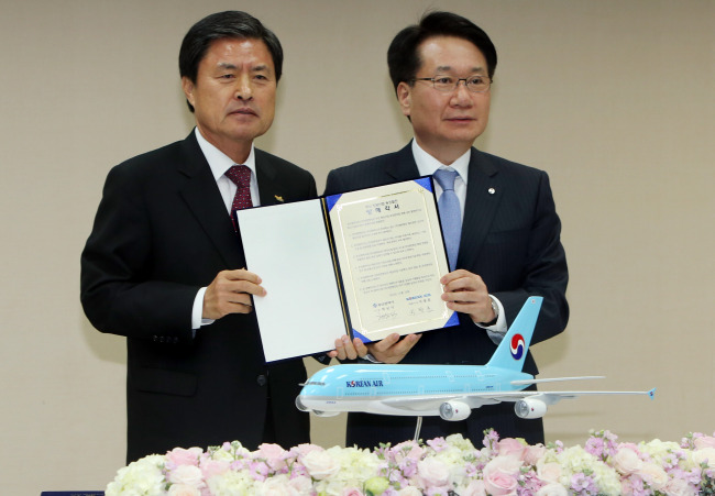 Korean Air president Ji Chang-hoon (right) and Busan Mayor Huh Nam-sik pose after signing an MOU at the City Council building on Monday.   Korean Air