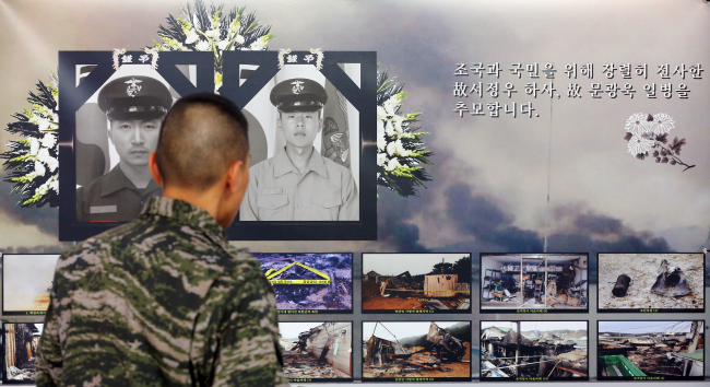 A soldier looks at pictures of soldiers killed during North Korea’s artillery attack on Yeonpyeongdo on Nov. 23, 2010, in an exhibition to mark its second anniversary, at Gimpo Airport, Tuesday.   Yonhap News