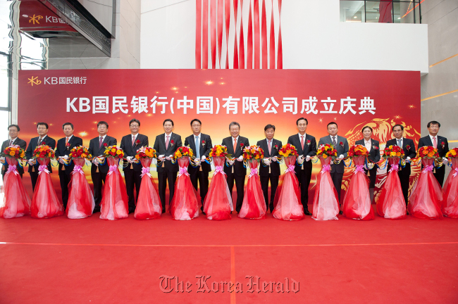 KB Financial Group chairman Euh Yoon-dae (eighth from left), company executives and Chinese officials attend a ceremony to open a Beijing branch of KB Kookmin Bank on Wednesday.   KB