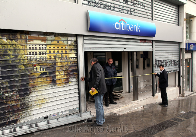 A man measures the metal shutters at the entrance to a Citigroup Inc. Citibank branch in Athens.   Bloomberg