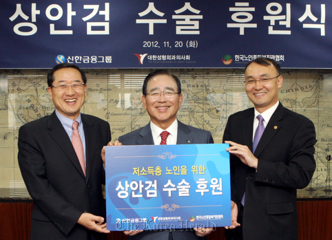 Shinhan Financial Group chairman Han Dong-woo (center) attends a ceremony to mark the lender’s support for elderly people’s eyelid surgery on Tuesday.   Shinhan Financial Group
Shinhan Financial Group chairman Han Dong-woo (center) attends a ceremony to mark the lender’s support for elderly people’s eyelid surgery on Tuesday.   Shinhan Financial Group