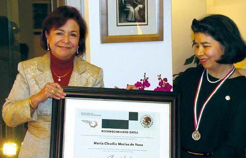 Mexican Ambassador to Korea Martha Ortiz de Rosas (left) and Seoul
National University professor Claudia Macias de Yoon hold up a plaque
Marcias de Yoon received with the Ohtli Award, which she is earing around her neck, during a reception at the ambassador’s residence in Seongbukdong in Seoul, Wednesday. (Philip lglauer/The Korea Herald)