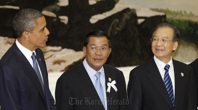U.S. President Barack Obama (left) chats with China's premier Wen Jiabao (right) as Cambodia's prime minister Hun Sen stands between them during a family photo at the East Asia Summit in Phnom Penh on Nov. 20. (AP-Yonhap News)