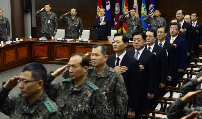 Defense Minister Kim Kwan-jin (third from left, back row) and top military commanders pledge allegiance to the national flag before holding their biannual gathering at the ministry in Seoul on Tuesday.   Park Hae-mook/The Korea Herald