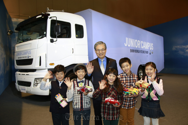 BMW Korea CEO Kim Hyo-joon poses with children in front of the specially designed Junior Campus truck at a COEX exhibition hall in southern Seoul on Thursday.   BMW Korea