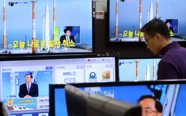 A man at an electronics shop in Yongsan, Seoul, watches TV news reports about the cancellation of the Naro space rocket’s launch due to a technical problem on Thursday afternoon.   Yonhap News