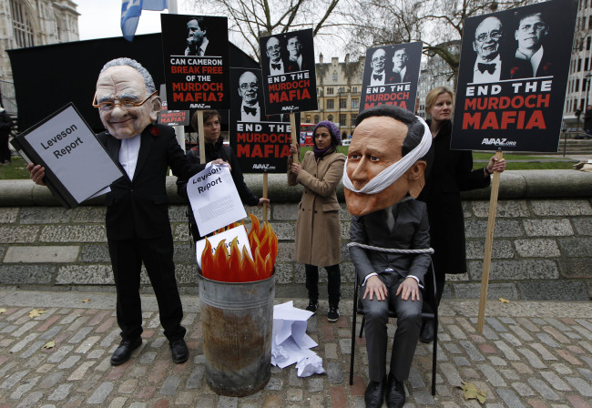 Campaigners wearing masks depicting News Corporation chairman Rupert Murdoch and British Prime Minister David Cameron call on MPs to back legislation to stop media monopolization, outside the Queen Elizabeth II Conference Center in London, Thursday.   AP-Yonhap News