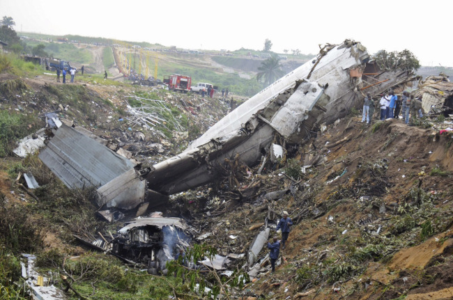 Rescue workers walk among the crash site of a cargo airplane near the airport at Brazzaville, Republic of Congo, Saturday.   AP-Yonhap News