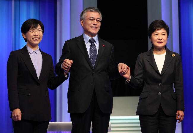 <YONHAP PHOTO-1637> 여야 대선주자 첫 TV토론회 (서울=연합뉴스) 이지은 기자 = 새누리당 박근혜, 민주통합당 문재인, 통합진보당 이정희 대선후보가 4일 오후 서울 여의도 MBC 스튜디오에서 중앙선관위 주최로 열린 첫 TV토론에 앞서 포즈를 취하고 있다. 이날 토론의 주제는 정치ㆍ외교ㆍ안보ㆍ통일 분야이다. 2012.12.4 jieunlee@yna.co.kr/2012-12-04 19:56:30/ <저작권자 ⓒ 1980-2012 ㈜연합뉴스. 무단 전재 재배포 금지.>
Presidential candidates Park Geun-hye (from right) of the Saenuri Party, Moon Jae-in of the Democratic United Party and Lee Jung-hee of the Unified Progressive Party clasp hands ahead of the first of their three television debates on Tuesday.   National Assembly photo pool