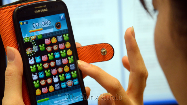 A female office worker plays a mobile game on her smartphone.   Chung Hee-cho/The Korea Herald