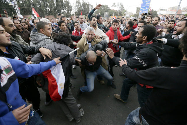 Egyptian President Mohammed Morsi’s supporters beat an opponent (center) during clashes outside the presidential palace in Cairo on Wednesday.  AP-Yonhap News