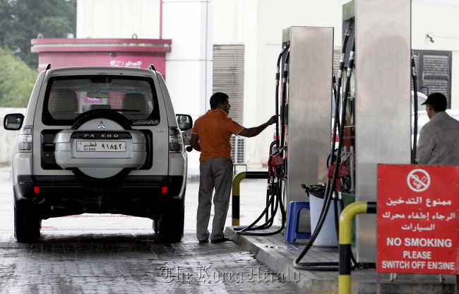 In this Dec. 1 photo, a man fills up his tank at a gas station in Doha, Qatar. The host of the current U.N. climate talks, Qatar is among dozens of nations that keep gas prices low through subsidies that exceeded $500 billion globally last year.   AP-Yonhap News