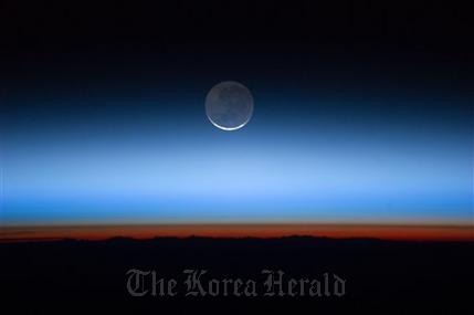 This undated image made available by NASA and photographed by the Expedition 28 crew aboard the International Space Station, shows the moon, at center with the limb of Earth near the bottom transitioning into the orange-colored troposphere, the lowest and most dense portion of the Earth’s atmosphere. A team of former NASA executives are launching a private venture to send people to the moon for $1.5 billion. The newly formed business is offering countries a two-person trip to the moon, either for research or national prestige.   AP Photo/NASA