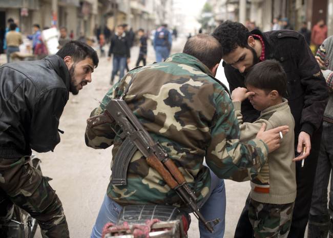 Seven-year-old Walid (right) is comforted as he mourns a fallen Syrian rebel fighter taken away for burial in the al-Fardos area of Aleppo on Saturday.   AFP-Yonhap News