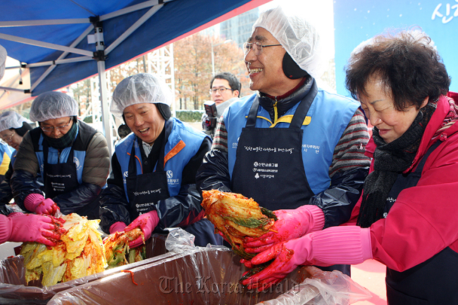 Shinhan Financial Group chairman Han Dong-woo (second from right) makes kimchi with the chief executives of affiliated companies on Thursday at Seoul’s Cheonggye Plaza.   Shinhan Financial Group