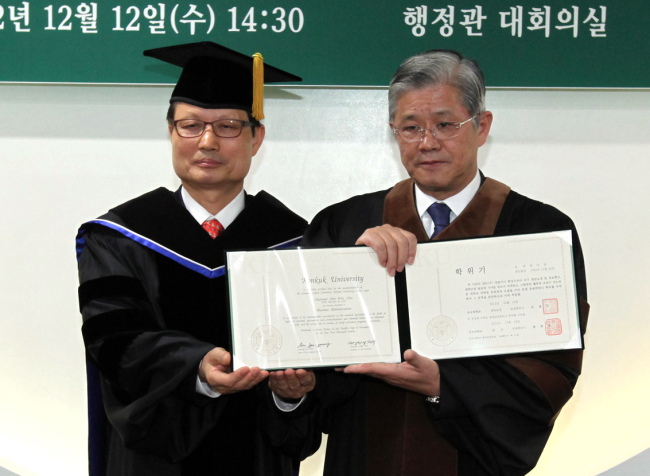 SKC chairman Choi Shin-won (right) poses with Konkuk University president Song Hee-young, holding his honorary doctorate.  Yonhap News