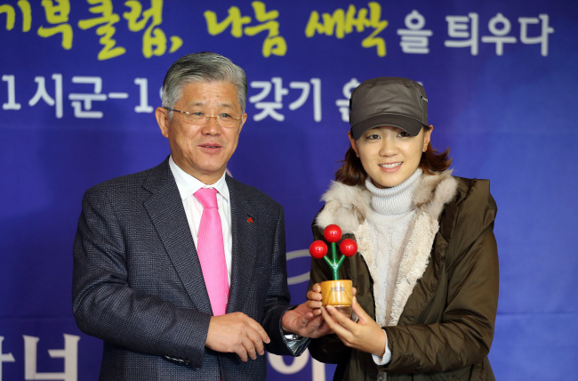 LPGA Tour golfer Choi Na-yeon (right) holds a statuette signifying her Honor Society membership she received from SKC and SK Telesys chairman Choi Shin-won (left), head of the Gyeonggi Province chapter of the Community Chest of Korea, in Seoul on Thursday.   Yonhap News