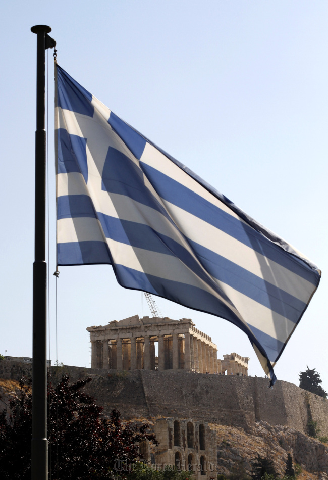 The Greek national flag flies at the foot of Acropolis hill in Athens.   Bloomberg