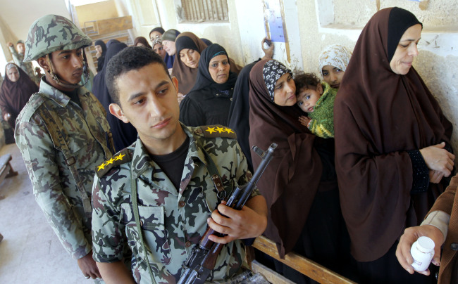 An Egyptian army officer stands near women as they prepare to vote for the second round of a referendum on a disputed constitution drafted by Islamist supporters of President Mohammed Morsi in Giza, Egypt on Saturday.   AP-Yonhap News