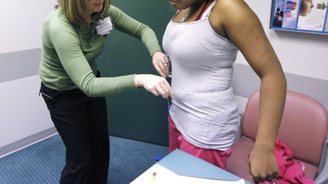 A nurse measure a girl's waistline. (AP)