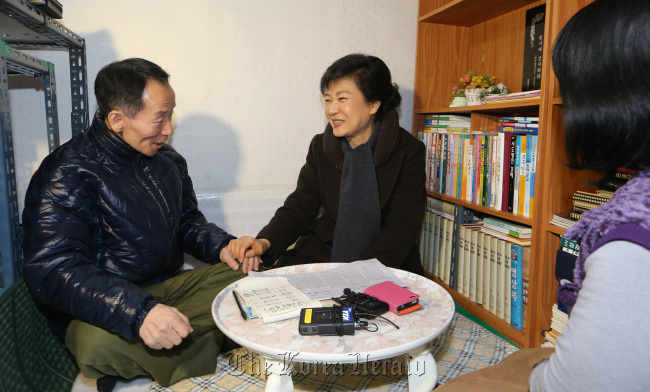 President-elect Park Geun-hye holds the hand of a recipient of the government’s livelihood subsidy for low-income earners at his home in Gwanak-gu, western Seoul, after delivering him a meal Monday.   Joint Press Corp.