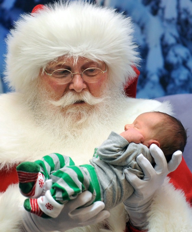 A man dressed as Santa Claus holds 1-week-old Zachary Nicolson for a Christmas visit at Twelve Oaks Mall on Saturday. (AP-Yonhap News)