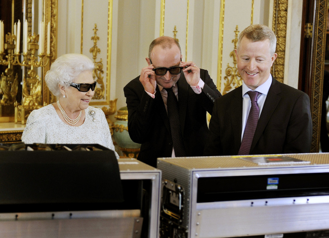 Britain’s Queen Elizabeth II wears 3-D glasses with producer John McAndrew (center) and director John Bennett in Buckingham Palace in London as they watch the recording of her Christmas message to be broadcast in 3-D for the first time.   AP-Yonhap News